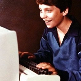 Dane DeValcourt as a kid, grinning at an early home computer